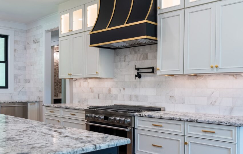 bright, traditional kitchen with black and warm neutrals featuring a black Hoodsly sloped hood with brass strapping